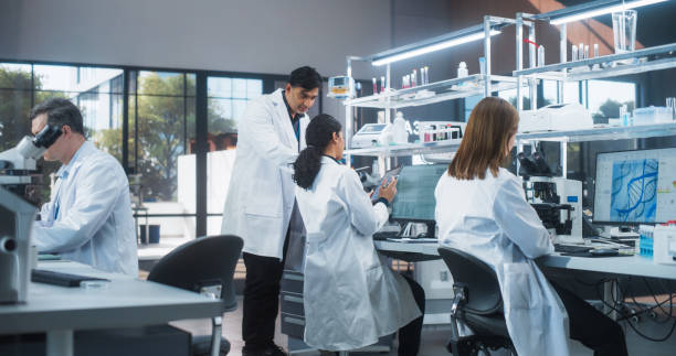 istock Female Research Scientist Having a Conversation with an Bioengineer About the Effects of Different Pharmaceutical Drugs. Employees Looking at a Computer Software in a Modern Science Laboratory 2190228264