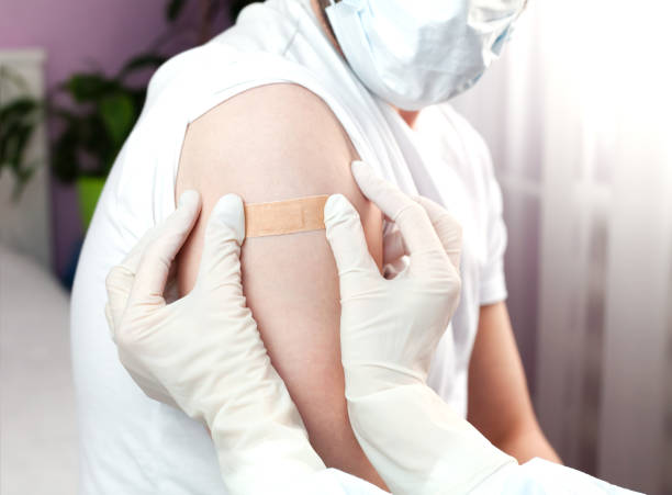 istock A doctor in white rubber protective gloves putting a plaster on a man's hand after an injection or vaccination. Health care. Covid-19 vaccination. Close-up. 2190231897