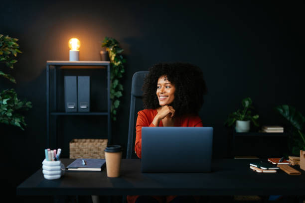 istock Smiling businesswoman looking away while working at laptop in modern office 2190232089