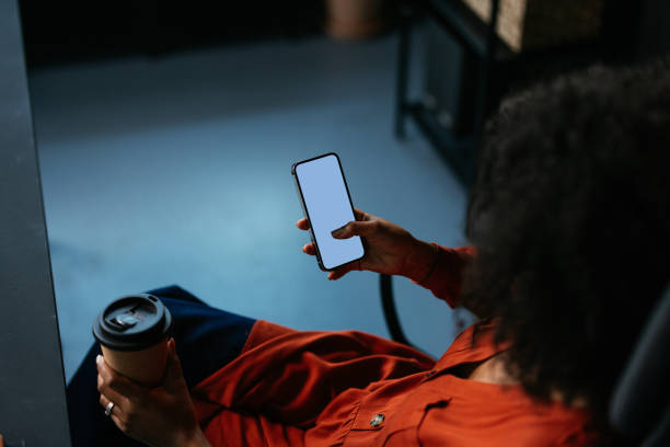 istock Businesswoman using smartphone and drinking coffee in office 2190232096