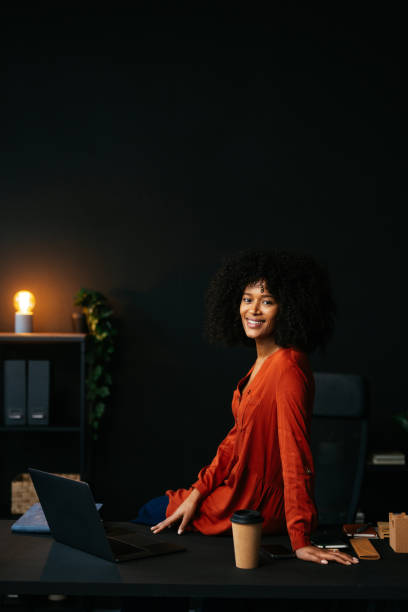 istock Young manager smiling sitting on desk in modern office 2190232098