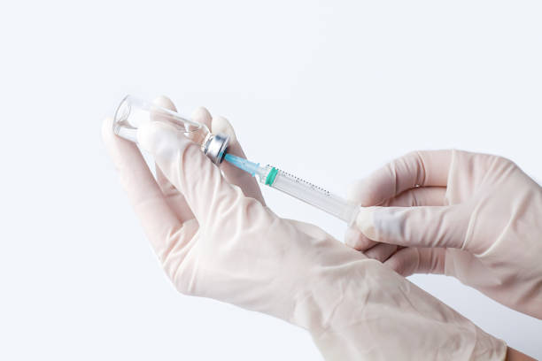 istock Doctor's or nur's hand in white protective gloves hold syringe with preparation for injection on the white background. Influenza and coronavirus vaccination. Close-up. Copy space. 2190232117