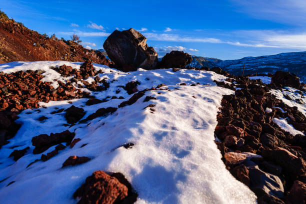 Lava Rocks at Sunset Scenic Landscape - Golden hour light on sidelit rocks, snow patches and mountain views.