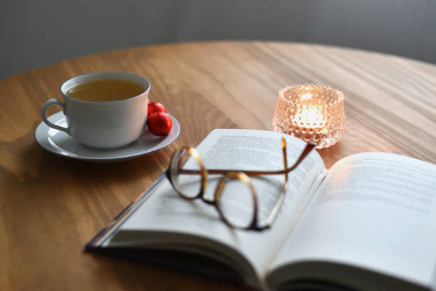 istock Open book with eyeglasses cup of tea and candle 2190239863