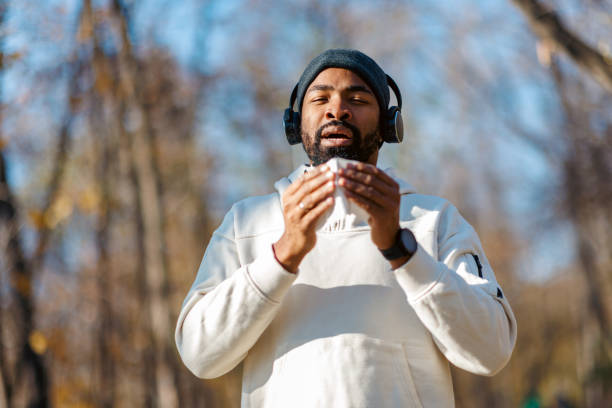 Young man blowing his nose while exercising outdoors