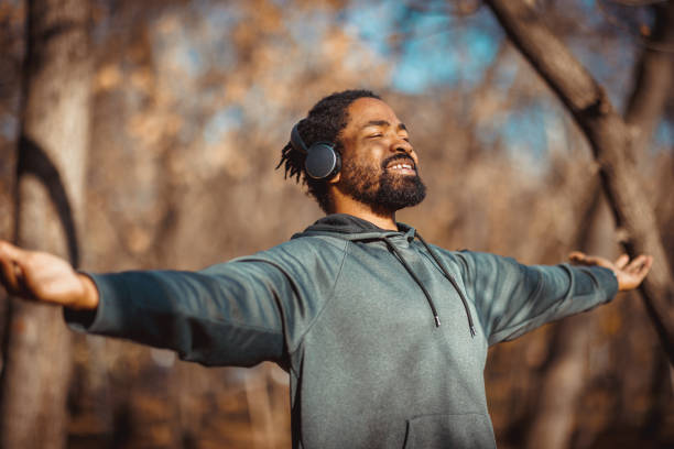 istock Young man enjoying music and exercising in nature with open arms 2190253694