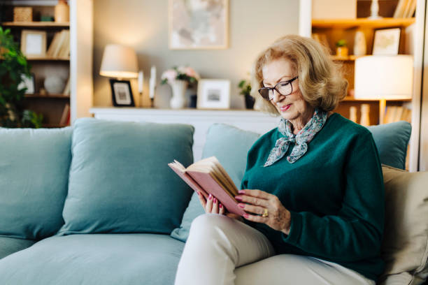 istock Senior woman reading book, sitting on sofa and resting at home 2190257121