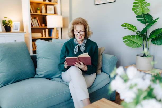 istock Senior woman reading book, sitting on sofa and resting at home 2190257168