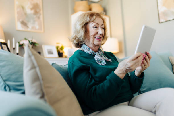 istock Shot of an elderly female sitting and using her tablet at home 2190257412