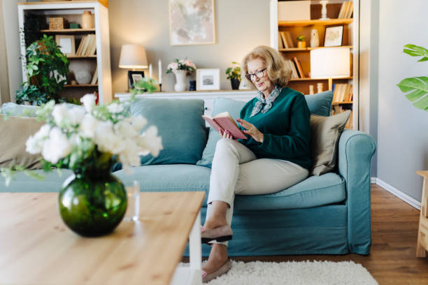 istock Senior woman reading book, sitting on sofa and resting at home 2190257659