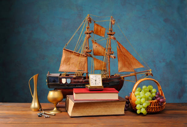 istock Still life, sailing ship model, books, metal cup and grapes 2190259159