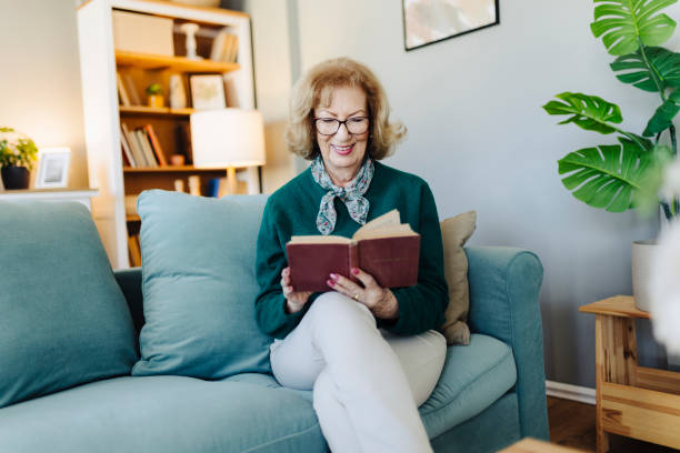 istock Senior woman reading book, sitting on sofa and resting at home 2190260606
