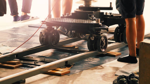 istock Camera trolley or camera dolly cart rails for filmmaking on studio shooting set. Pro videographer dolly rail track for filming movie mounted on studio floor. Video production dolly and crews in set. 2190264002