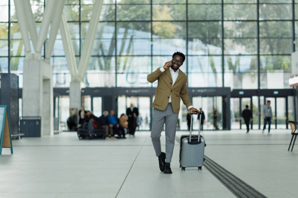 istock Man Walking Indoors With Suitcase and Smartphone in Modern Terminal 2190267169
