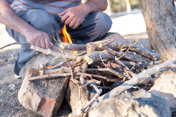 Person Starting a Campfire with Sticks in an Outdoor Setting