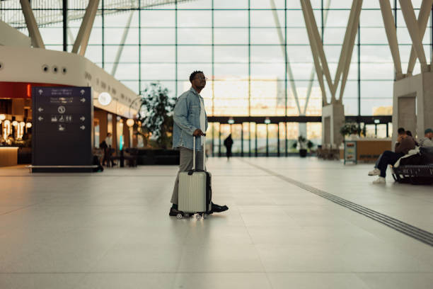 istock Traveler in Modern Airport Terminal Pulling Suitcase 2190270128