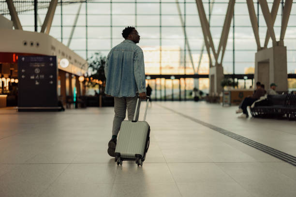 istock Man Walking Through Modern Airport With Suitcase Under Natural Light 2190270138