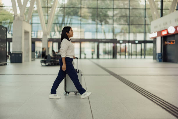 istock Woman Walking Through Modern Airport Terminal With a Carry-On Suitcase 2190270142