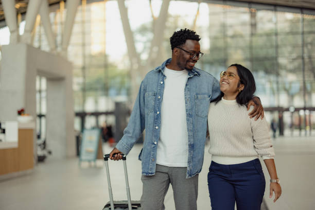 istock Smiling Couple With Luggage Walking Through a Modern Open-Plan Terminal 2190270158
