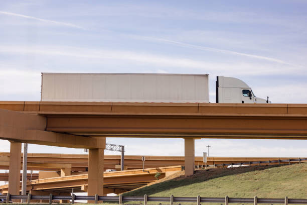 istock Semi Truck Driving Over an Elevated Highway Bridge Under Clear Skies 2190271734