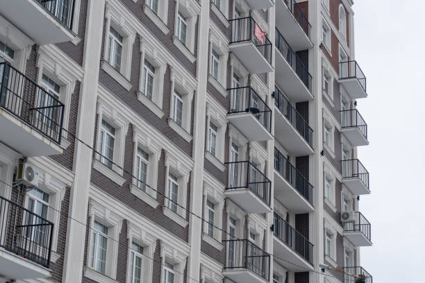 Snow blankets the ground as a modern residential building with multiple balconies stands in an urban landscape