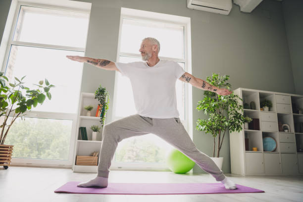 istock Senior man practicing yoga at home in comfortable activewear with bright daylight creating a peaceful atmosphere 2190274997