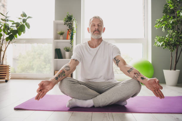 istock Calm middle-aged man meditating on yoga mat in peaceful home setting with plants and sunlight 2190275007
