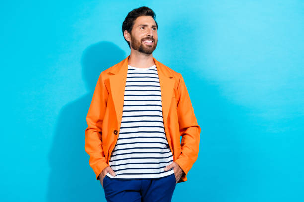 Confident man in orange jacket against turquoise background expressing casual style and charisma