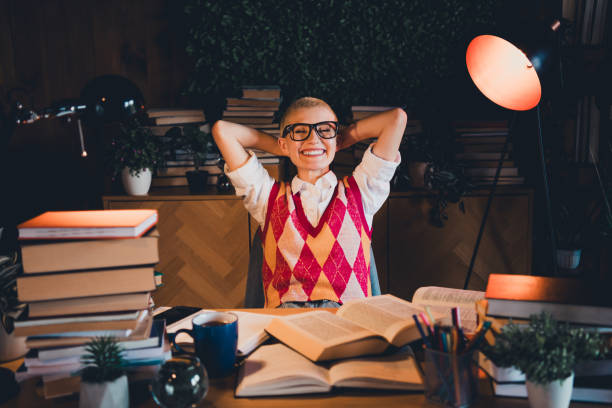 istock Young student wearing stylish argyle vest and glasses enjoys a study session at home, surrounded by books 2190275907