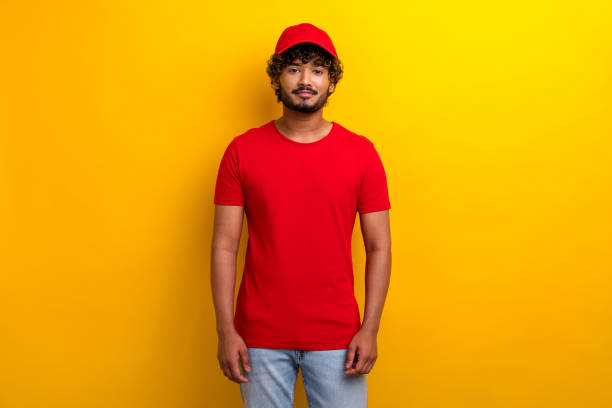 istock Trendy young man in red attire posing with confident expression against a vibrant yellow background 2190277542