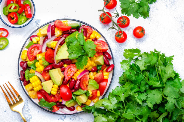 istock Corn salad with red beans, avocado, tomatoes, onion and cilantro. White background, top view 2190277712