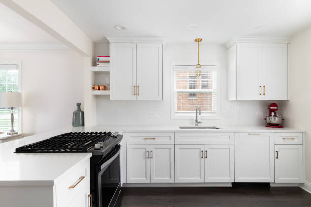 A white kitchen with gold accents and a herringbone tile backsplash.