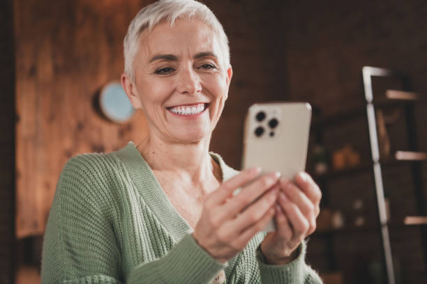 istock Elderly woman with gray hair smiling while using smartphone in cozy home setting 2190282100