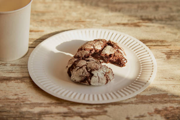 istock A plate with a broken half of a chocolate cookie with cracks on an old rustic wooden table in a beam of sunlight, with a disposable cup nearby, close-up, homemade baking, simple baking, rustic breakfast. 2190283203