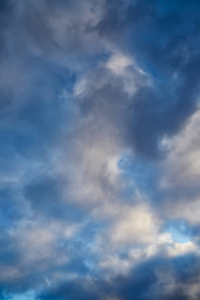 Soft sunlight highlights gray winter clouds against a bright blue sky. blur