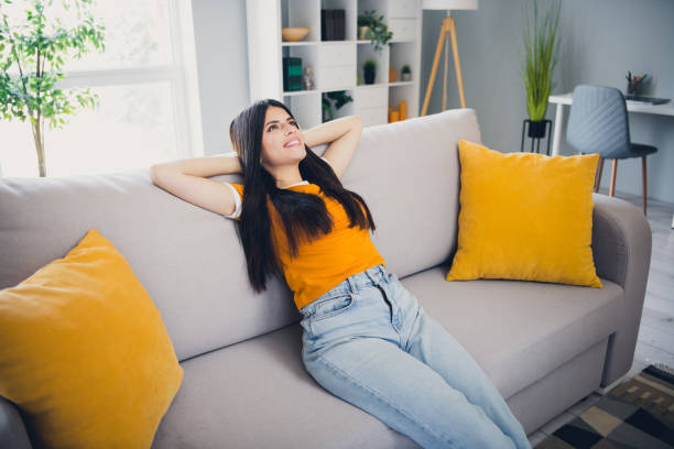 istock Young woman relaxing happily on a comfortable sofa during a sunny day indoors 2190283278