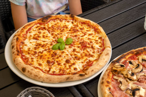 istock Close-up of Margherita pizza on a restaurant table with basil garnish, delicious authentic Italian cuisine, wood-fired pizza, dining outdoors, food photography, one person, classy casual setting 2190287249