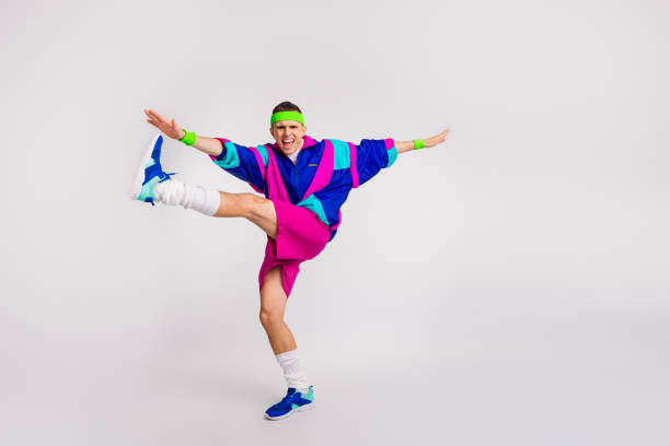 istock Energetic young man in retro activewear doing a dynamic exercise with enthusiasm and charming smile on a white background 2190289444