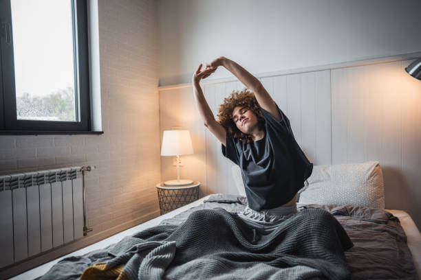 Young woman stretching in bed to start her day