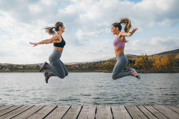 istock Two Women Exercising Outdoors Overlooking a Serene Lake Landscape 2190290907