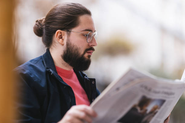 istock Bearded Man Reading a Newspaper Outdoors in Casual Attire 2190292193