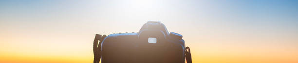 camera at sunset on tripod shooting beautiful sunny horizon with long exposure, background blurred with bokeh effect