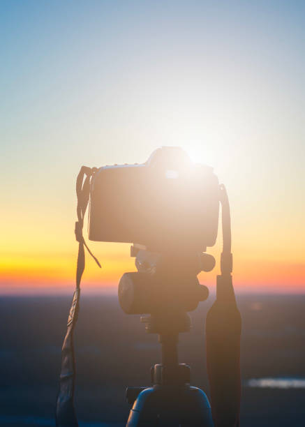 camera at sunset on tripod shooting beautiful sunny horizon with long exposure, background blurred with bokeh effect