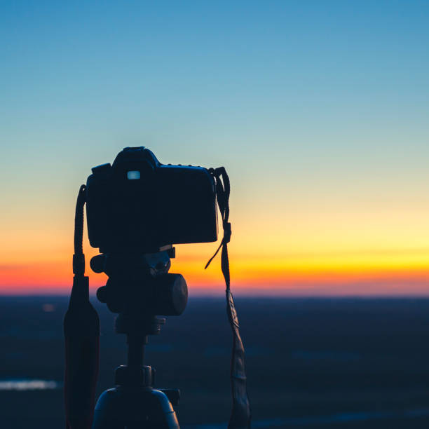 camera at sunset on tripod shooting beautiful sunny horizon with long exposure, background blurred with bokeh effect