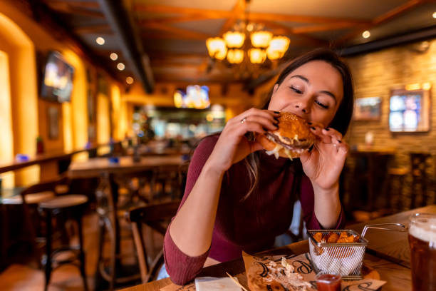 istock Young woman enjoying a delicious burger in a restaurant 2190296844