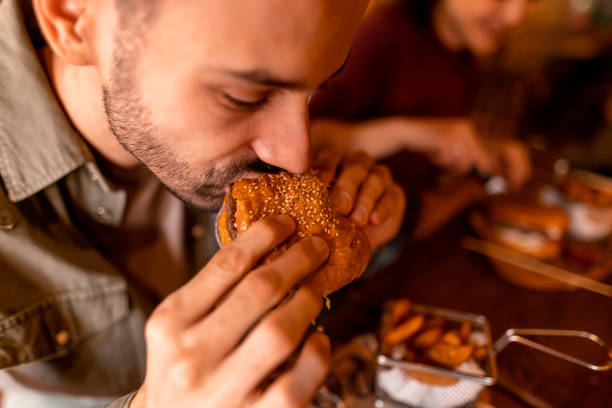 istock Young man enjoying a delicious burger at a restaurant 2190297791
