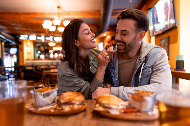 istock Young couple sharing fries and beer at restaurant table 2190297926