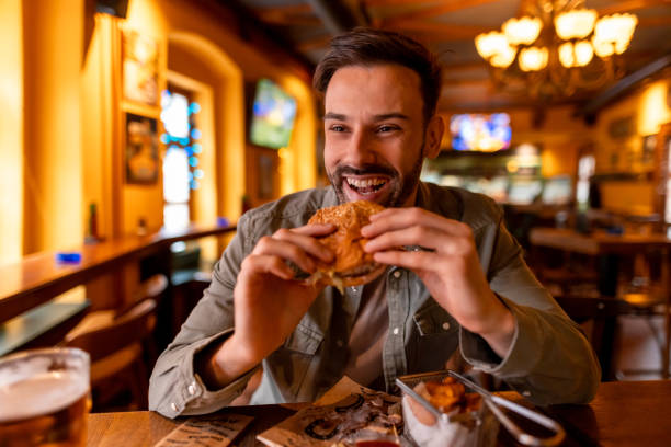 istock Cheerful young man enjoying a burger and beer at a restaurant 2190298169