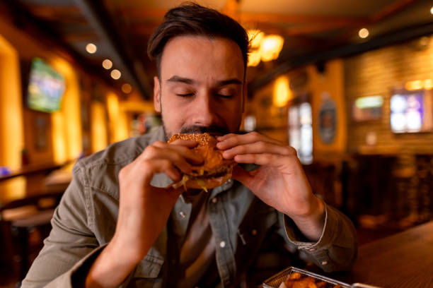 istock Young man enjoying a tasty burger at a restaurant 2190298172