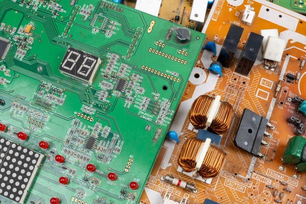 Detailed close-up of green and orange circuit boards with various electronic components showcasing technology recycling and electronic waste